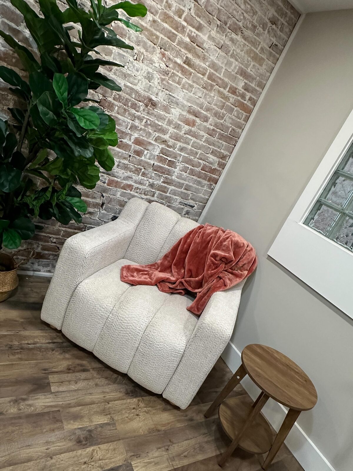 A cozy corner of the studio: brick, a white boucle chair and a plant